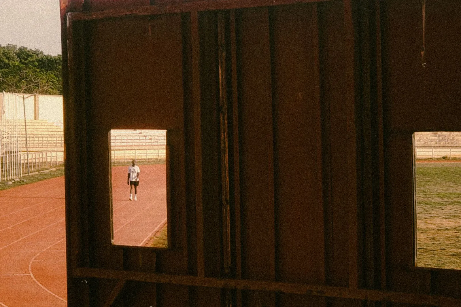Lone runner on a red track framed by a rusty scoreboard