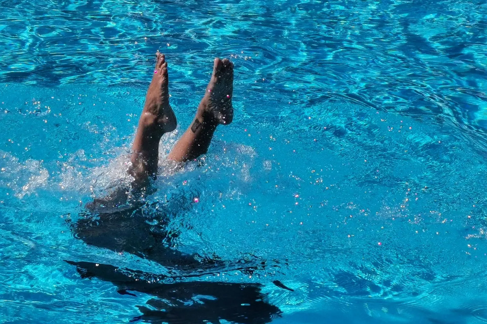 Diver entering a bright blue pool with a splash